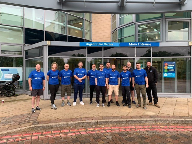 A large group of people stand outside of Hexham Hospital's main entrance, wearing blue shirts.